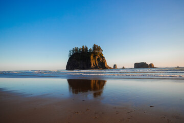 Scenic view of Second Beach at sunset in Olympic National Park, Washington State. Dramatic sea stacks, golden sky, and peaceful waves along the rugged Pacific Northwest coast.