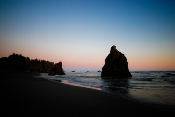 Sunset at Ruby Beach, Olympic National Park, Washington State. Colorful sky reflecting on wet sand with sea stacks and gentle ocean waves.