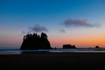 Scenic view of Second Beach at sunset in Olympic National Park, Washington State. Dramatic sea stacks, golden sky, and peaceful waves along the rugged Pacific Northwest coast.