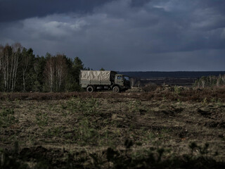 Obraz premium Military truck positioned on heathland terrain with dramatic cloudy sky background