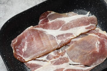 Raw smoked back bacon rashers on a non stick roasting tray.