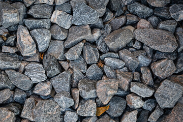 Close-up of grey granite stones forming a natural rough texture. Abstract background of crushed rock, construction material, and nature detail.