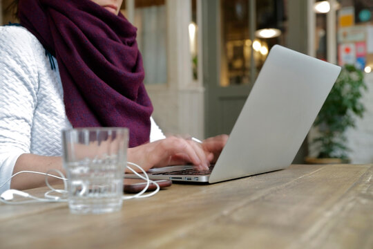 Person working on laptop in bright public space with modern interior design elements - Powered by Adobe