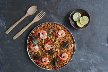Paella is a Spanish dish made from rice, seafood, shrimp, clams, lemon, peas with saffron seasoning.