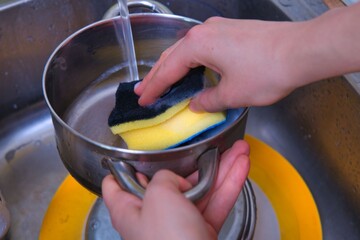 Washing Dishes Hands scrubbing a plate in a kitchen sink with soapy water