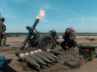 Military mortar firing with soldiers operating equipment and artillery shells visible
