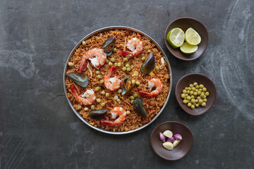 Paella is a Spanish dish made from rice, seafood, shrimp, clams, lemon, peas with saffron seasoning.