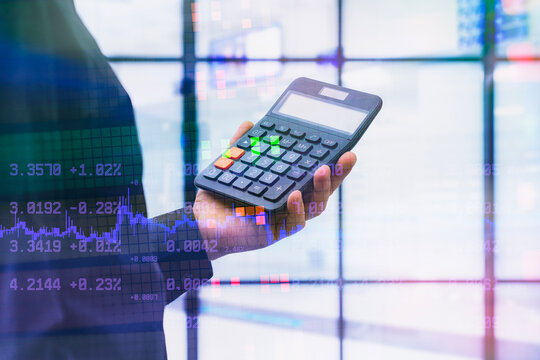 Businessman hand holding calculator with digital overlay of stock market charts and numbers. Concept of finance, cryptocurrency trading, accounting, investment planning and fintech. - Powered by Adobe