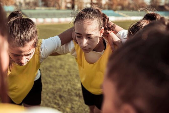 Teen soccer team huddling before match on outdoor field - Powered by Adobe