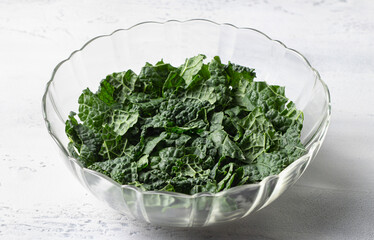 Fresh chopped kale leaves in glass bowl on white kitchen table