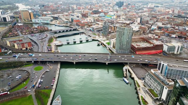 Aerial drone view of cars driving over the buildings surrounding River Lagan in Belfast, Northern Ireland