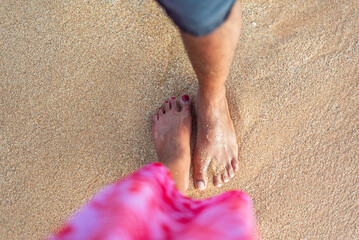 Couple standing barefoot on the beach enjoying the ocean waves