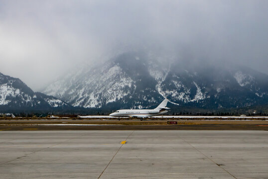 A plane on the runway with snowy mountains in Jackson Hole, Wyoming