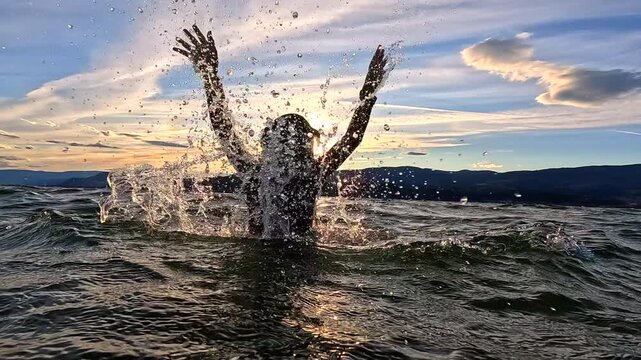Young girl jumping and splashing in Okanagan Lake Kelowna British Columbia Canada water slow motion travel vacation dusk slow motion - Powered by Adobe