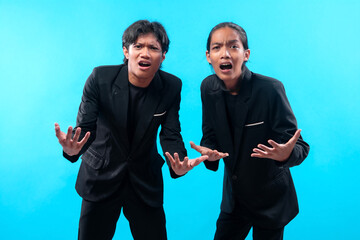 Two Asian men in black suits standing against a blue background, both showing confused and frustrated expressions with open hands, symbolizing argument, stress, and conflict.