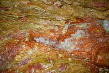 Outcrops of variegated clay in a stream, water running over clay surface