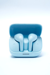 Modern wireless earphones in blue charging case, isolated on white background, symbolizing music, lifestyle, technology, and portable audio convenience.