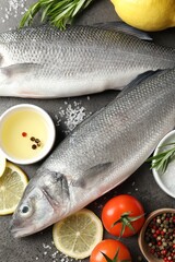 Fresh raw seabass with spices on grey table, closeup. Fish and seafood delicacies
