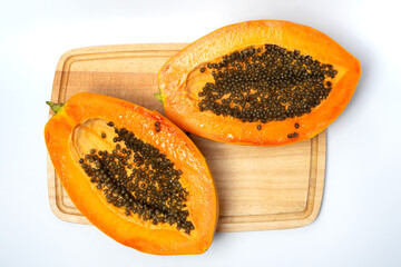 Fresh ripe papaya fruit cut in half on a wooden cutting board, showing vibrant orange flesh and black seeds, symbolizing tropical nutrition and healthy food.