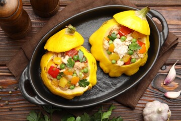 Tasty stuffed pattypan squashes in baking dish on wooden table, flat lay