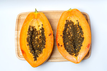 Ripe papaya fruit cut in half on a wooden board with bright orange flesh and black seeds, symbolizing tropical freshness, organic nutrition, exotic taste, and healthy natural food choice.