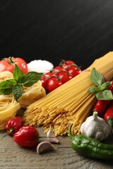 Different types of pasta and ingredients on wooden table, closeup