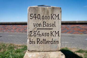 Historic stone milestone on the Rhine River between cologne and dusseldorf, showing distances to Basel and Rotterdam