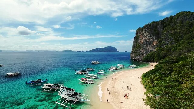 Aerial view of crescent-shaped tropical beach and boats in El Nido, Palawan, Philippines Curved beach with boats and turquoise water in El Nido, Palawan, Philippines