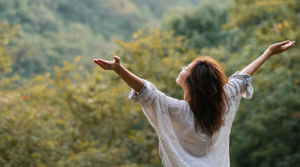 Happy serene woman embracing nature outdoors with open arms in peaceful forest