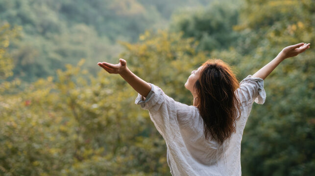 Happy serene woman embracing nature outdoors with open arms in peaceful forest