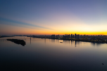 Skyline view of Wuhan, China, at sunset across the wide river water.