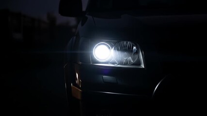 Modern car headlight turning on and off in the darkness with focus transition, bright white lights