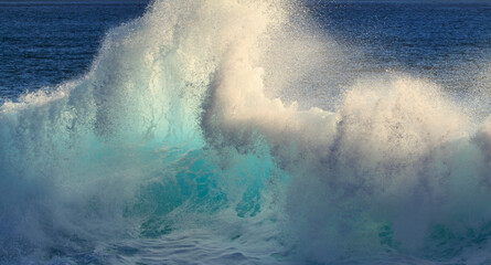 Obraz premium Giant ocean wave illuminated by sunset light. Enormous ocean wave rising high with golden sunset tones, showcasing the dramatic strength, power, and beauty of nature at sea.