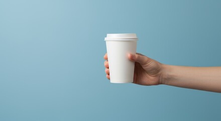 A Simple Morning Gesture: Hand Holding a White To-Go Coffee Cup on a Calm Blue Backdrop
