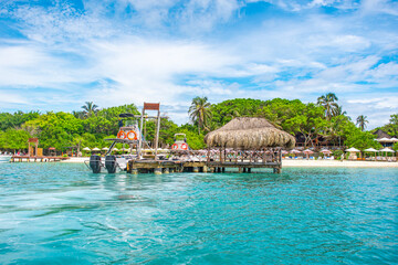 A picturesque dock on Rosario Island, featuring a thatched-roof hut, turquoise waters, and lush greenery in Cartagena, Colombia.