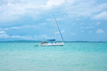 A sailboat anchored in the tranquil waters of Rosario Islands near Cartagena, Colombia, under a beautiful cloudy sky.