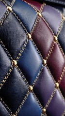 Close-up of quilted leather with gold studs and stitching in various shades of blue and purple