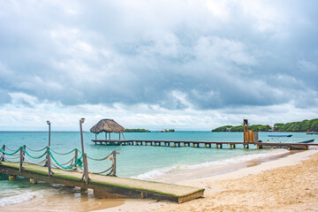 A serene view of a tropical beach in Rosario Islands, Cartagena, featuring wooden piers, sandy shores, and calm turquoise waters.