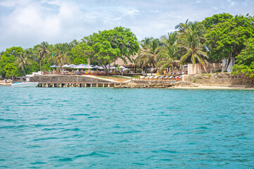 A scenic view of a tropical beach resort in the Rosario Islands, featuring palm trees and clear blue water, ideal for vacation imagery.