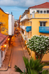 A picturesque street in Cartagena, Colombia, showcasing vibrant buildings and beautiful flowers at dusk.