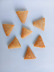 Top view of cone-shaped crispy snacks. Salty, textured corn chips arranged on a white background, an ideal concept for savory appetizers or junk food.

