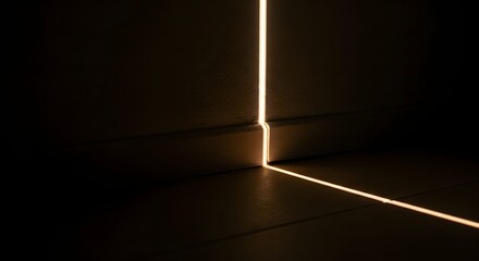A narrow beam of bright light illuminates a dark room, escaping from under a closed door and casting a long line across the floor.