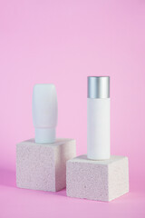 Plastic white tube for cream or lotion. Skin care or sunscreen cosmetic with stylish props on pink background.
