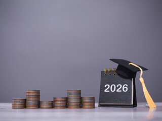 2026 Desk calendar with graduation hat and stack of coins. The concept of saving money for education, student loan, scholarship, tuition fees in year 2026