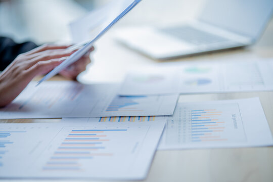 Business colleagues analyzing documents and charts at an office desk, focusing on planning, teamwork, financial analysis, cooperation, and decision-making.
 - Powered by Adobe