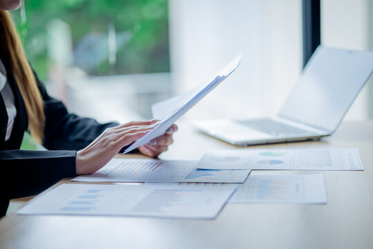 Business colleagues analyzing documents and charts at an office desk, focusing on planning, teamwork, financial analysis, cooperation, and decision-making.