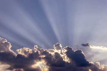 Dramatic sun rays breaking through dark clouds in the sky. Beatiful nature background with light...