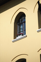 Obraz premium Decorative window with flowers on a yellow building facade