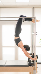 Fototapeta premium Asian woman doing aerial exercise on reformer machine. 