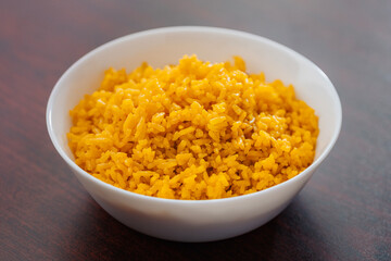 White Bowl of Yellow Rice on brown table